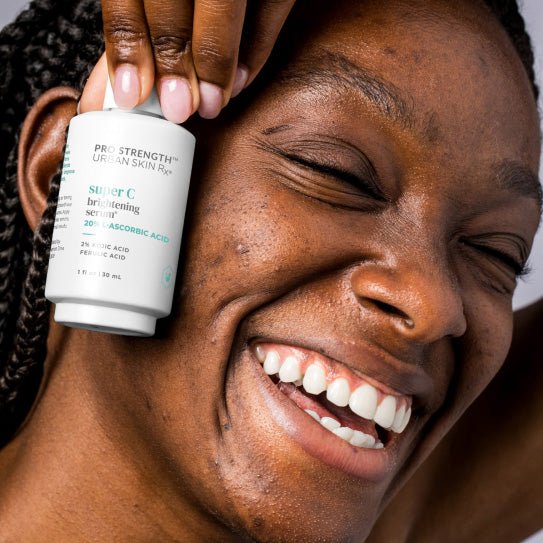 Woman holding a jar of USRx Super C Brightening Serum next to her face
