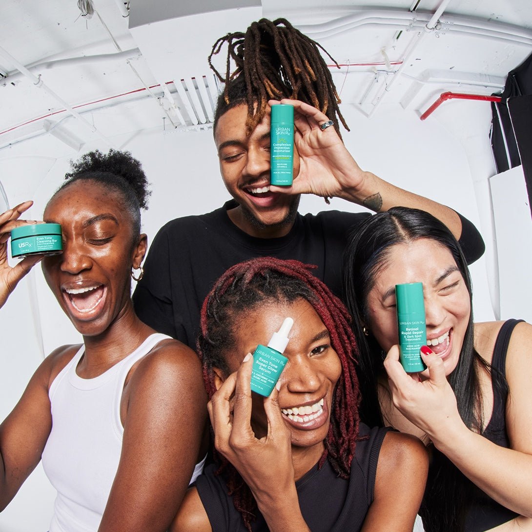 Four people smiling and holding different USRx skincare products against a white background
